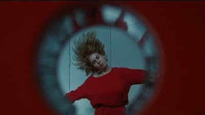 a woman in a red dress standing in front of a mirror
