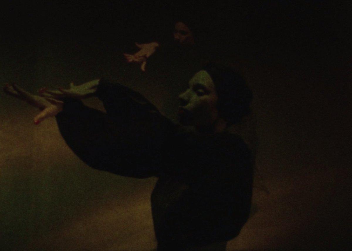 a man in a dark room with a bird flying above him