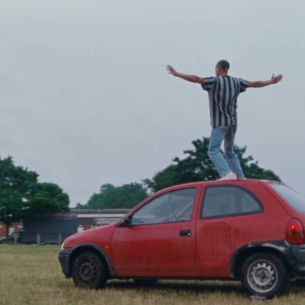 a man standing on top of a red car