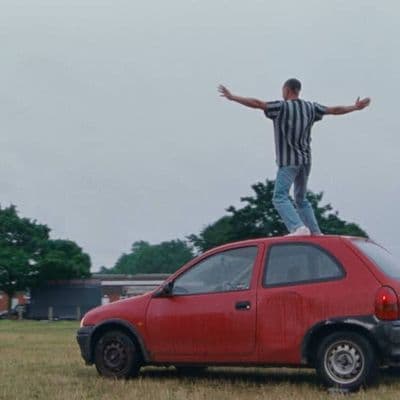 a man standing on top of a red car