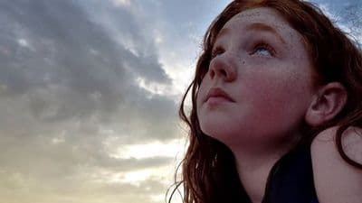 a girl looking up at a cloudy sky