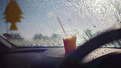a drink sitting on the dashboard of a car