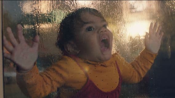 a little girl standing in front of a window