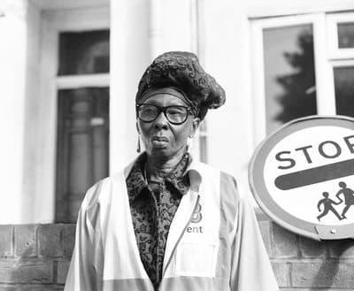 a black and white photo of a man in front of a stop sign