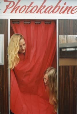 two women standing in front of a red curtain