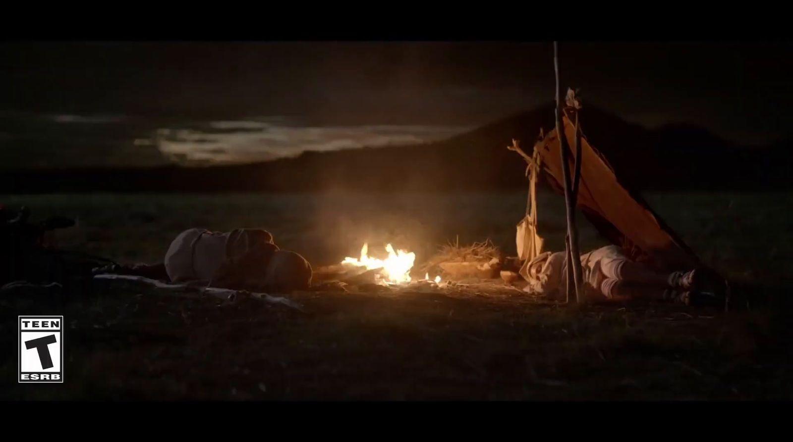 a person laying on the ground next to a campfire