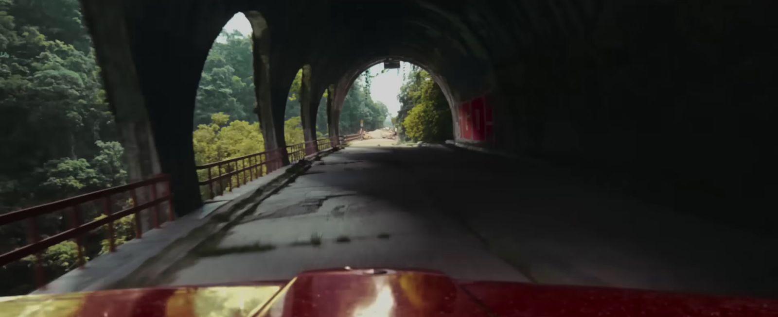 a car driving through a tunnel with trees on both sides