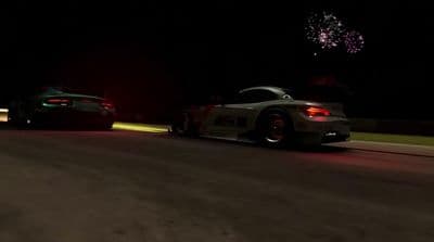 a couple of cars driving down a street at night