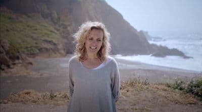 a woman standing on a beach next to the ocean