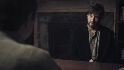 a man sitting at a table in front of a fire place