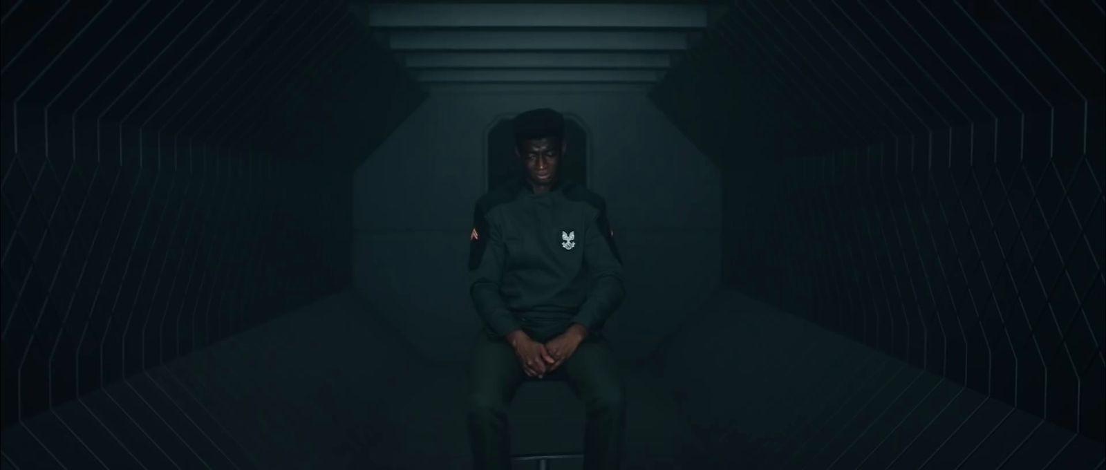 a person sitting in a dark room with a hoodie on