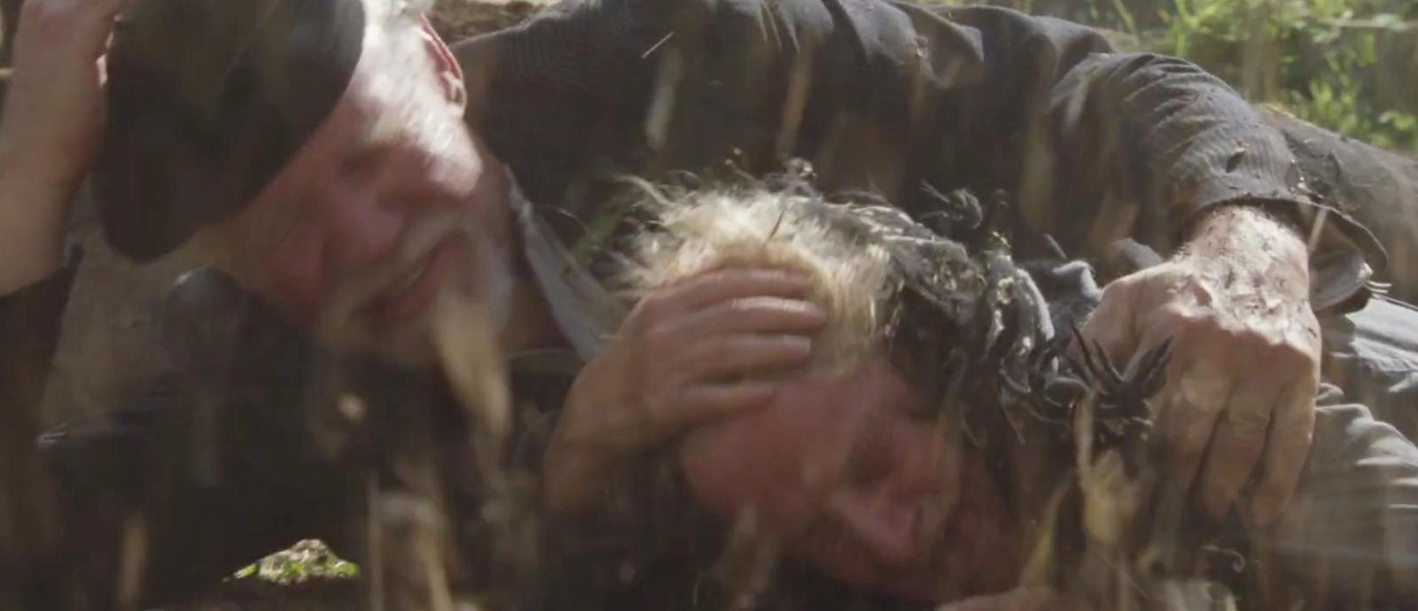 a man laying on the ground covered in mud