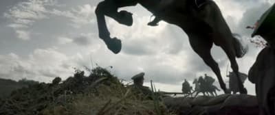 a man riding a horse over a pile of hay