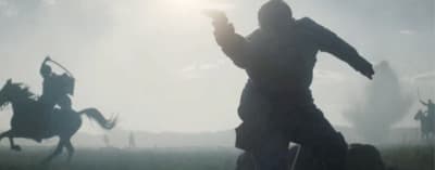 a silhouette of a man holding a gun in front of a group of horses