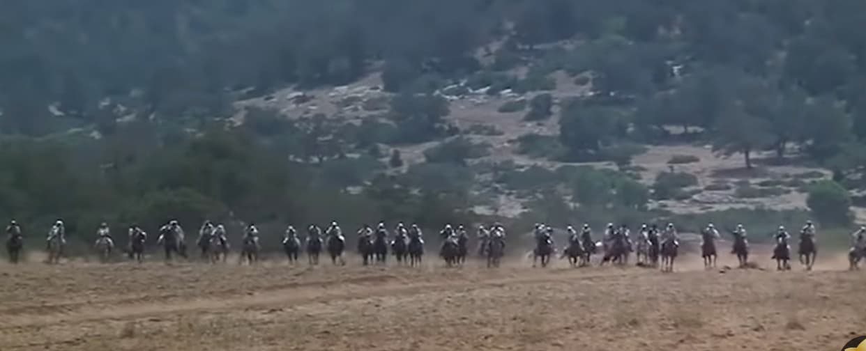 a group of people riding horses on a dirt field