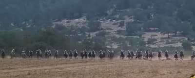 a group of people riding horses on a dirt field