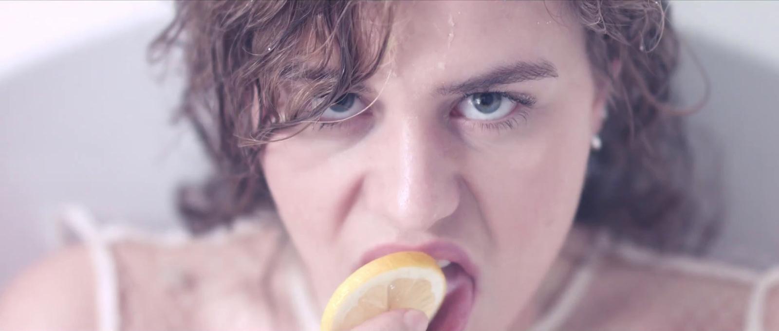 a woman with a lemon slice in her mouth