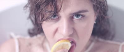 a woman with a lemon slice in her mouth