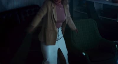 a woman standing in a dark room next to a couch