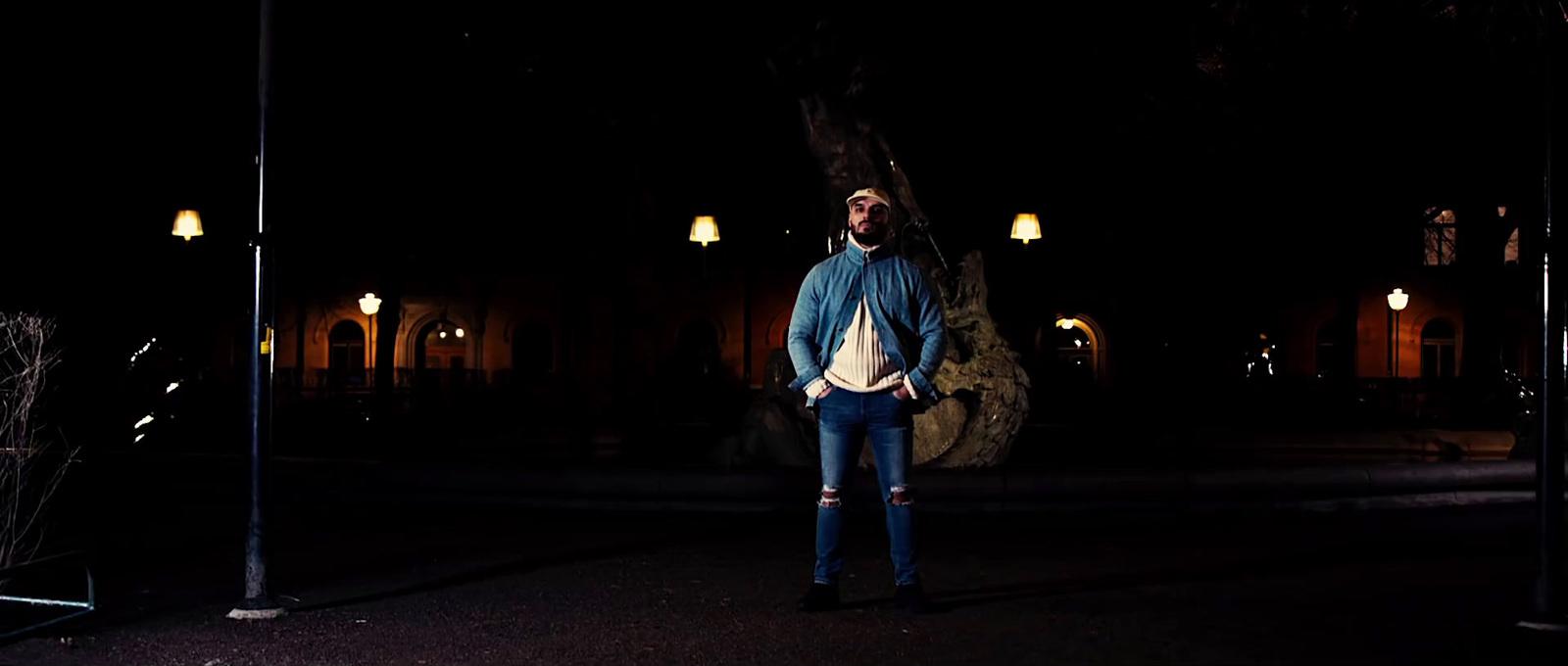 a man is standing in the dark with his hands in his pockets