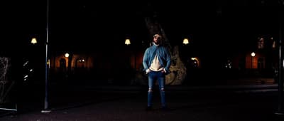 a man is standing in the dark with his hands in his pockets
