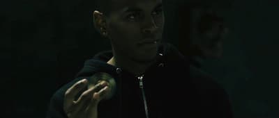 a man in a black hoodie holding a green object