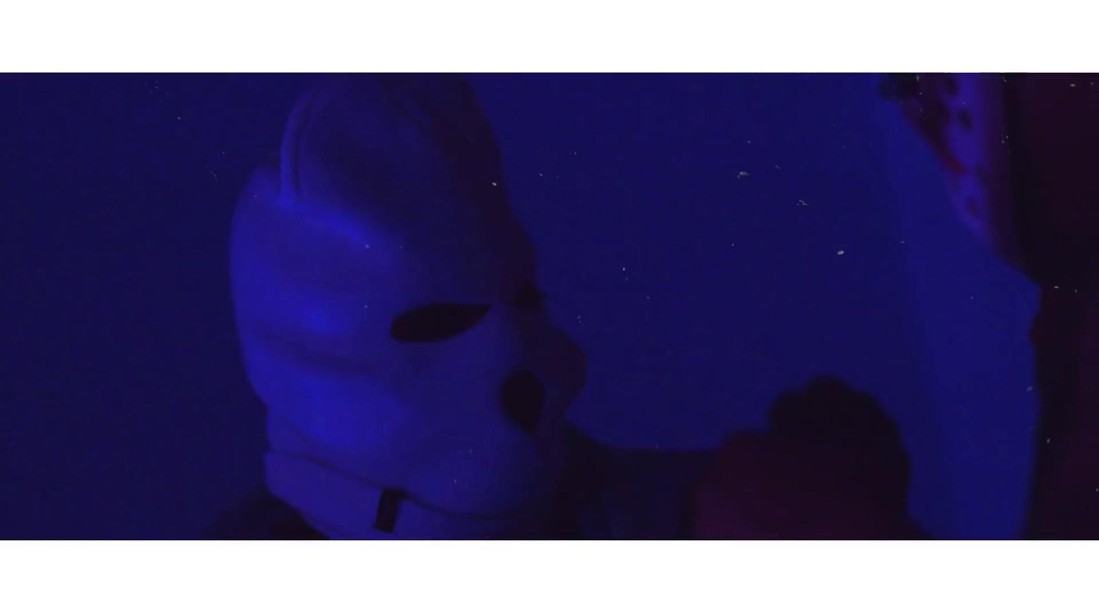 a person wearing a white mask in a dark room