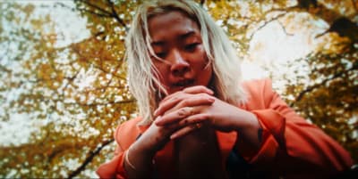 a woman holding her hands together in front of a tree
