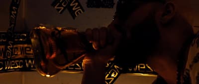 a man drinking from a glass in a dark room