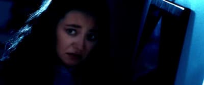 a woman looking at the camera in a dark room