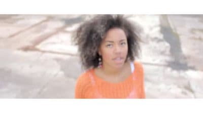 a woman with an orange sweater and earrings