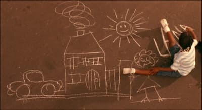 a child drawing a house on the ground with chalk