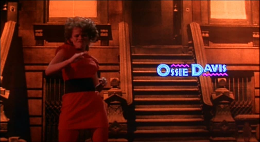 a woman in a red dress standing in front of stairs