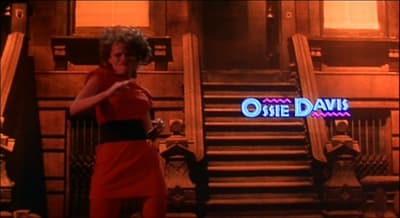 a woman in a red dress standing in front of stairs