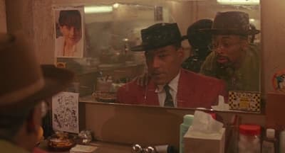 a man in a hat looking at himself in a mirror