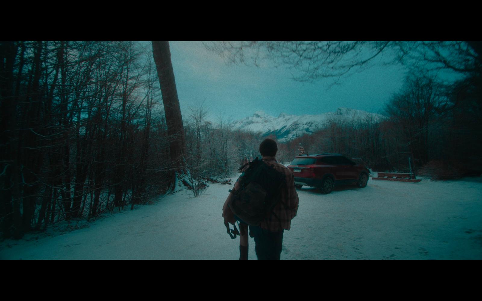 a person walking in the snow with a car in the background