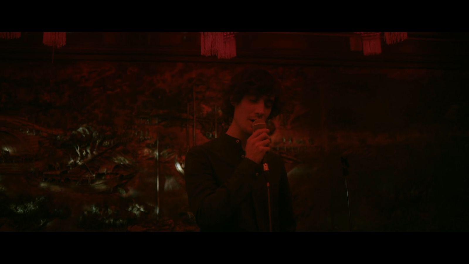 a man standing in front of a microphone in a dark room