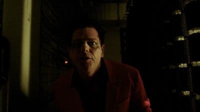 a man in a red jacket standing in a dark room