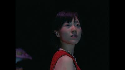 a woman in a red dress standing in the dark