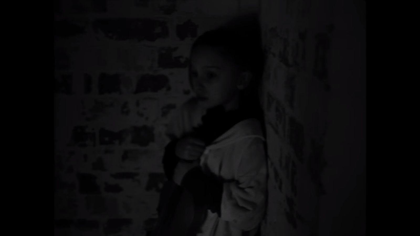 a woman standing in a dark room next to a wall