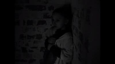 a woman standing in a dark room next to a wall