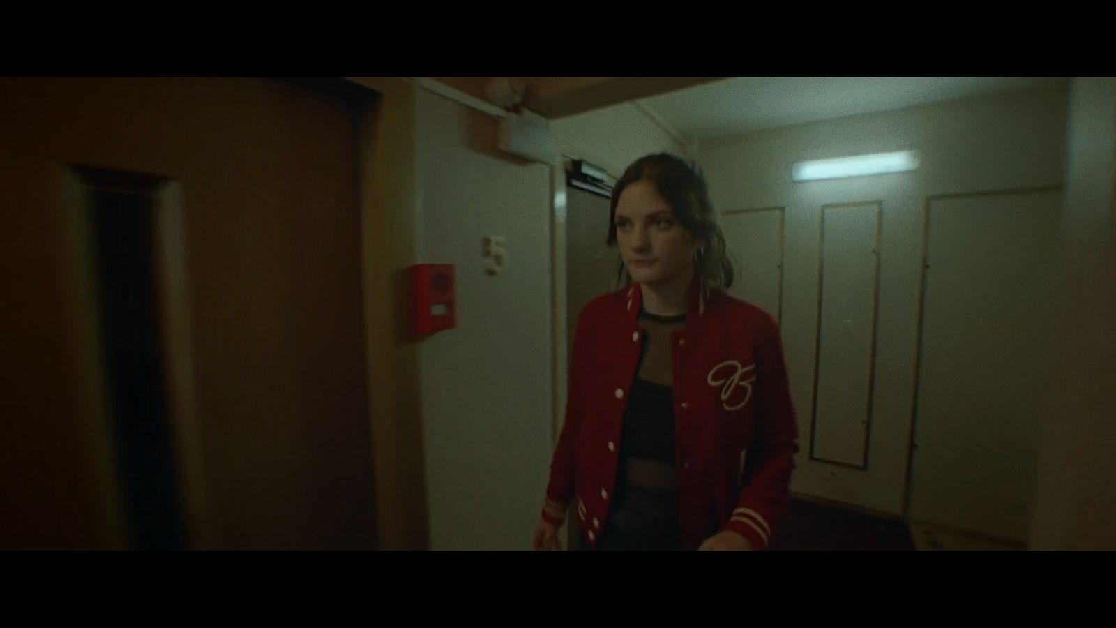 a woman in a red jacket standing in a hallway