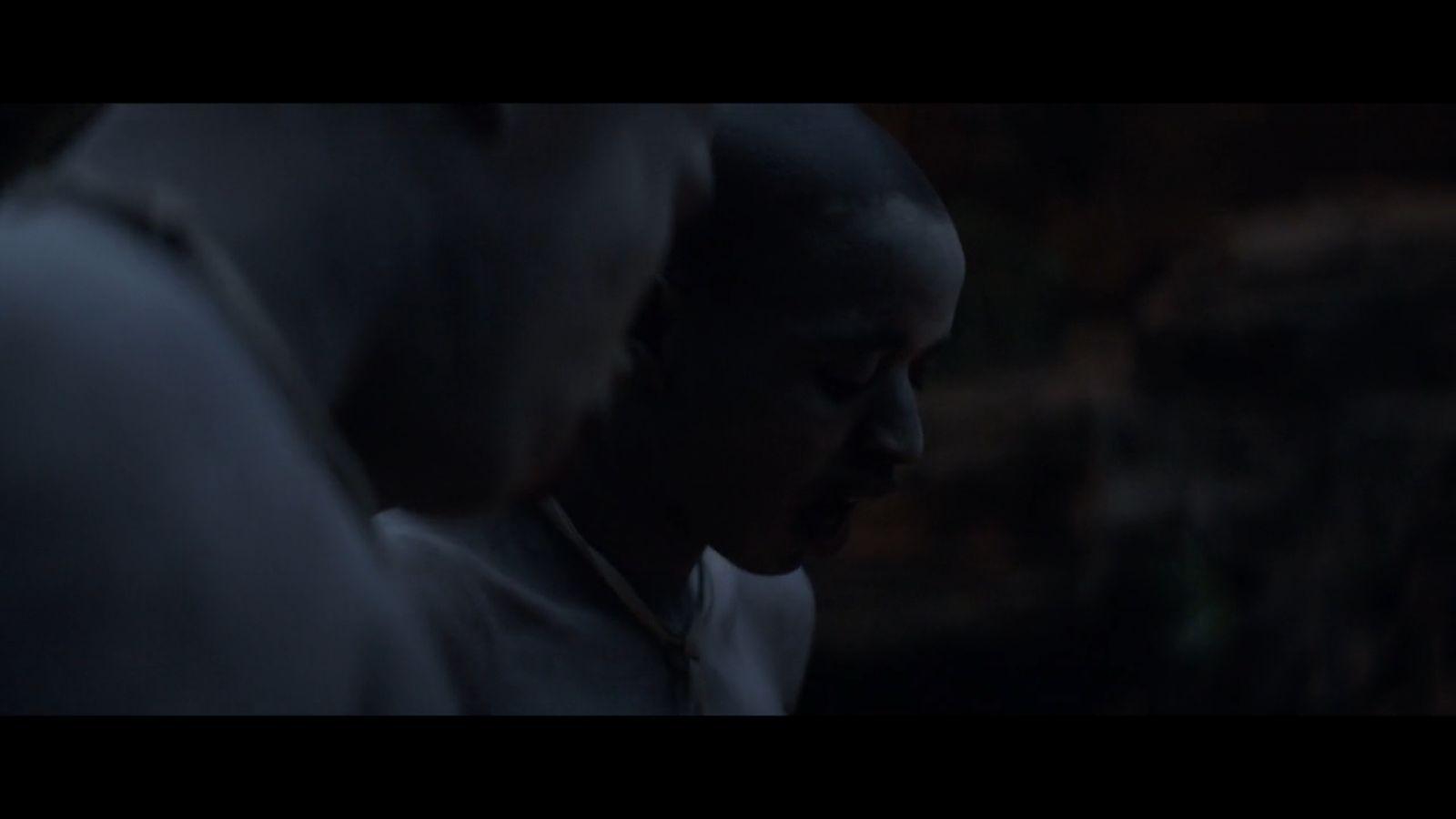 a man standing next to another man in a dark room