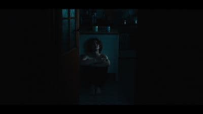 a woman standing in a dark room holding a cell phone