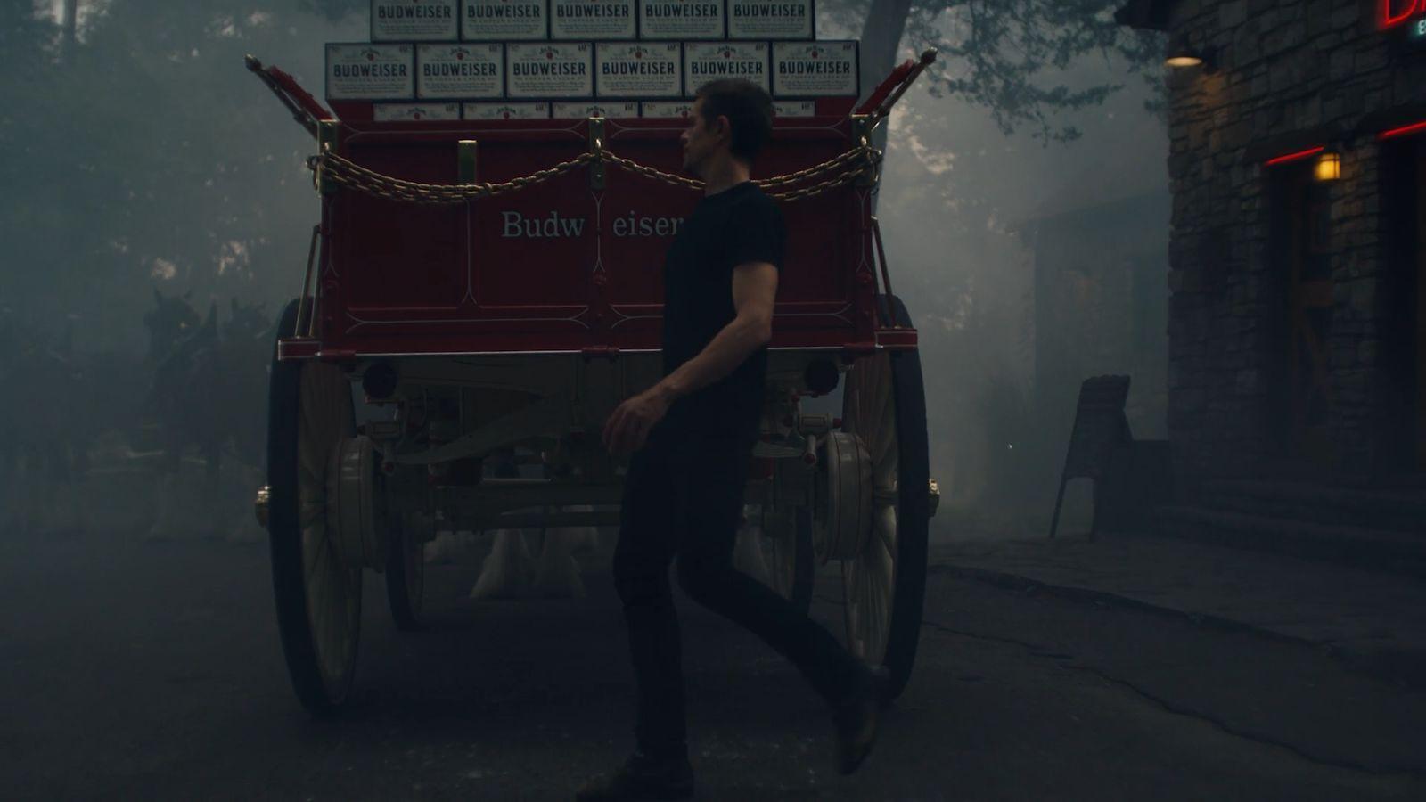 a man walking down a street next to a horse drawn carriage