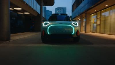 a green car is driving down a city street