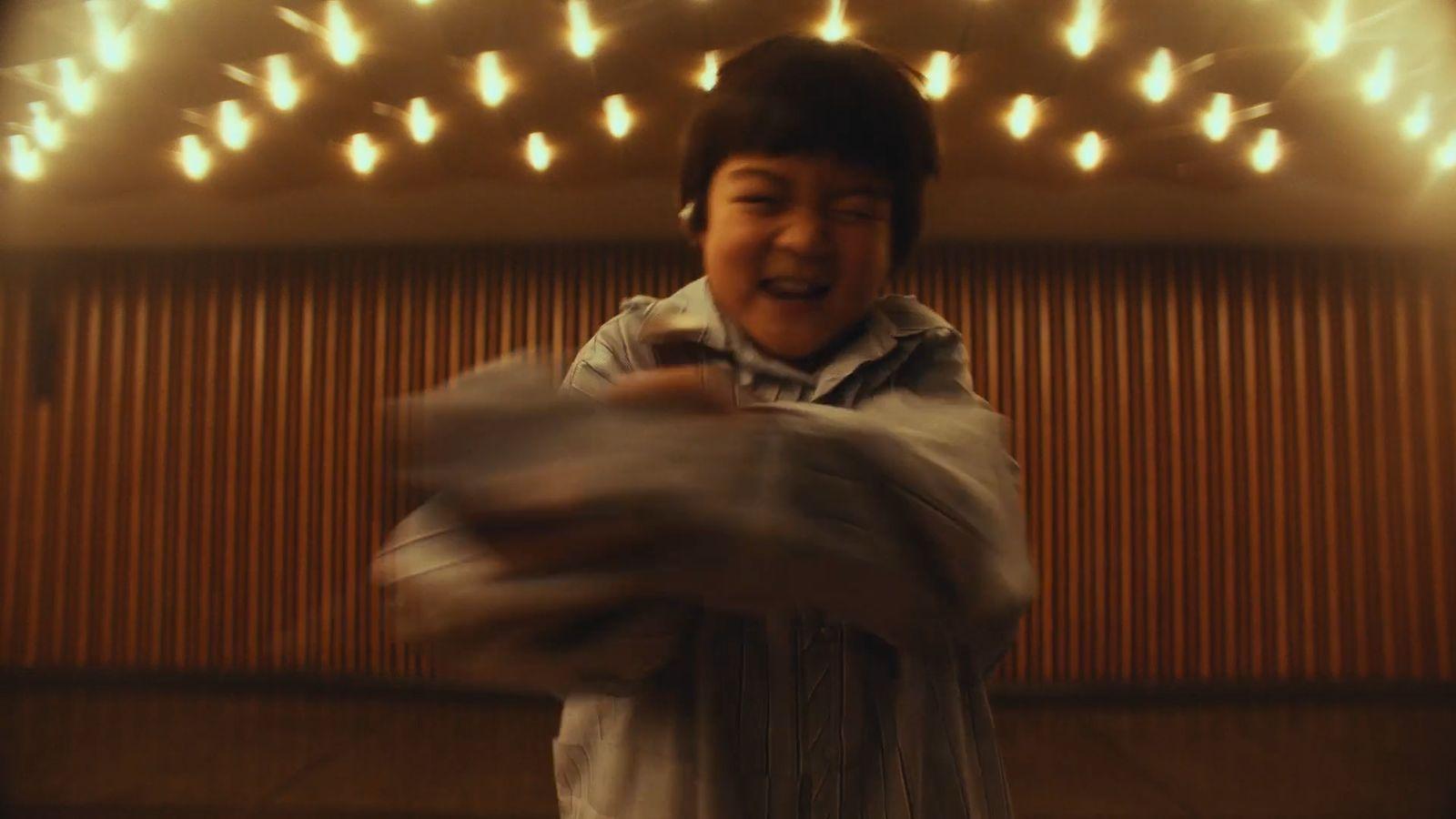 a young boy standing in front of a wall covered in lights