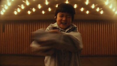 a young boy standing in front of a wall covered in lights