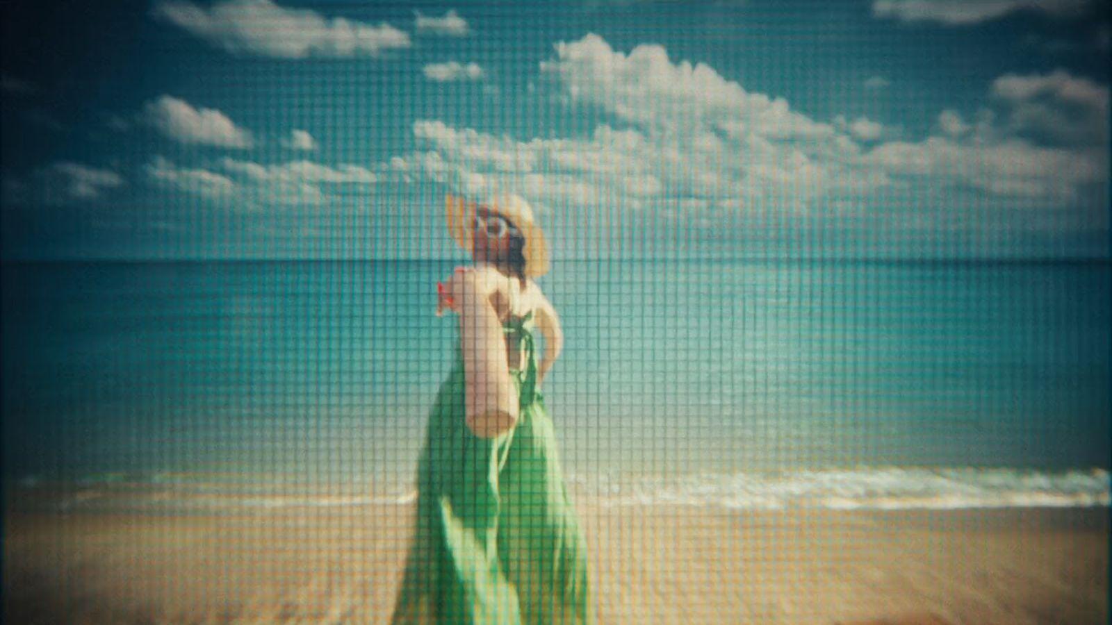 a woman in a green dress standing on a beach
