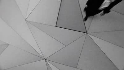 a black and white photo of a person walking on a tile floor